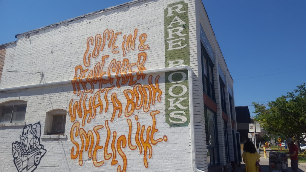 The wall of a building with text that reads, "Come in and Remember What a Book Smells Like"
