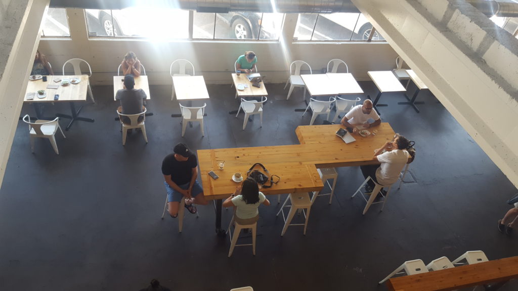 An aerial shot that shows people standing around a table and drinking coffee.