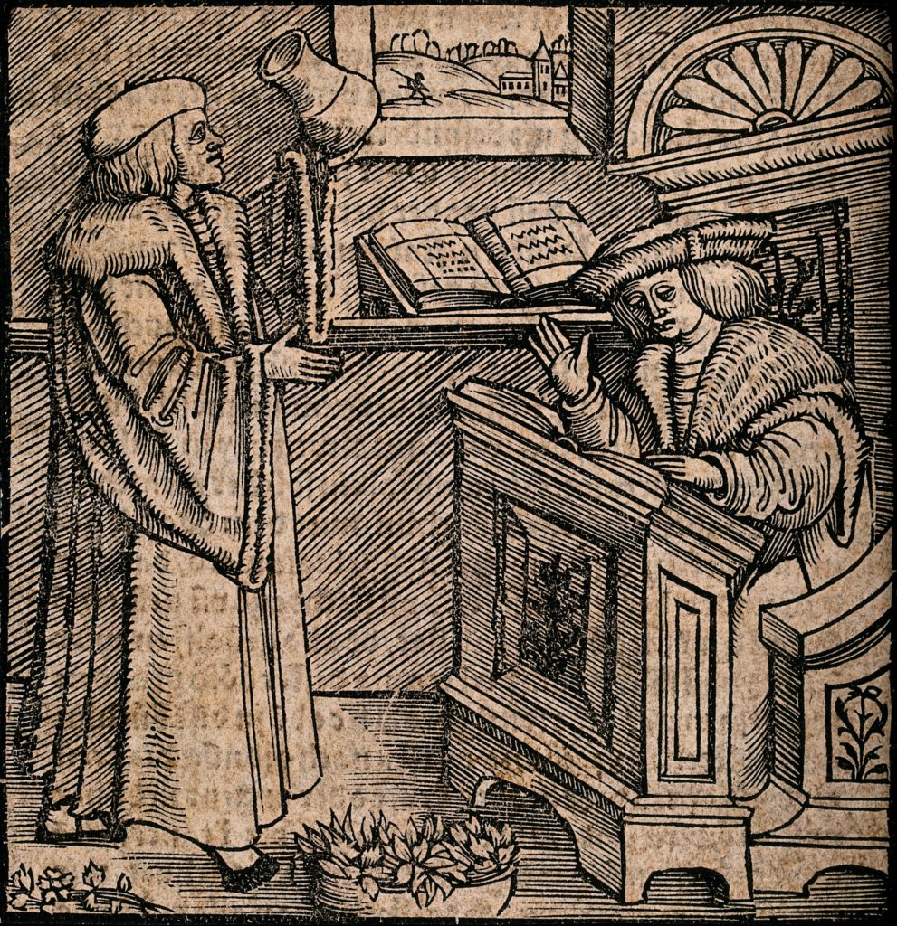 A man in a heavy cloak and hat is reading a large book which is resting on a lectern, another man nearby has a pot in his hand. Woodcut.