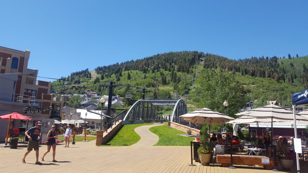 Landscape with mountain in background covered in green grass. Ski lift in foreground.